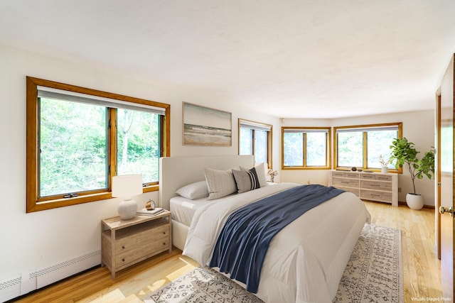 bedroom featuring a baseboard heating unit and light wood-type flooring