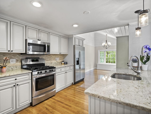 9 Cogswell Path, West Yarmouth, MA 02673 - kitchen with stainless steel appliances, a sink, a chandelier, light wood-type flooring, and backsplash