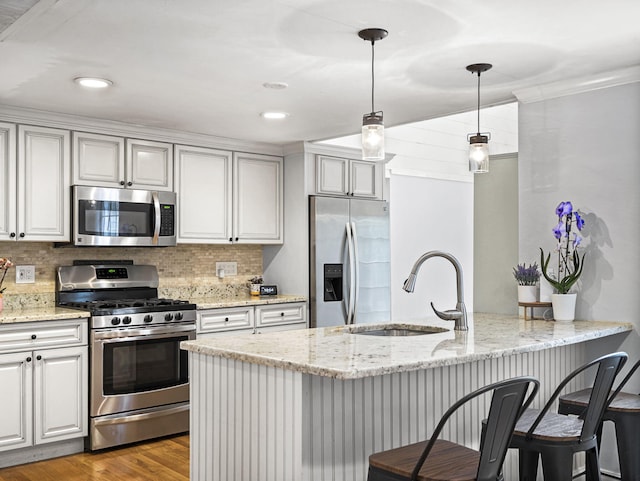 9 Cogswell Path, West Yarmouth, MA 02673 - kitchen with appliances with stainless steel finishes, a sink, a peninsula, backsplash, and light stone counters