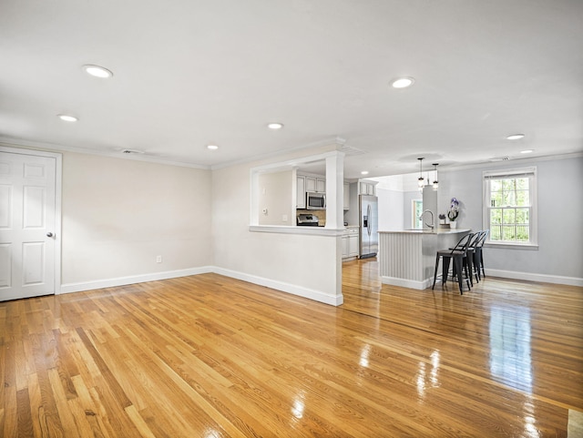 9 Cogswell Path, West Yarmouth, MA 02673 - unfurnished living room with recessed lighting, ornamental molding, light wood-type flooring, baseboards, and a sink