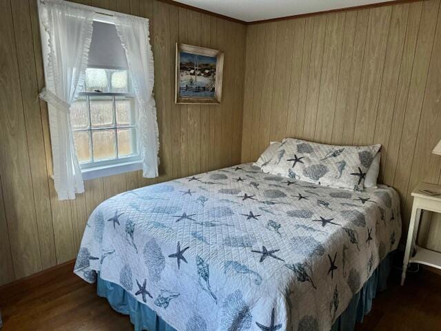 bedroom with wood walls and dark wood-type flooring