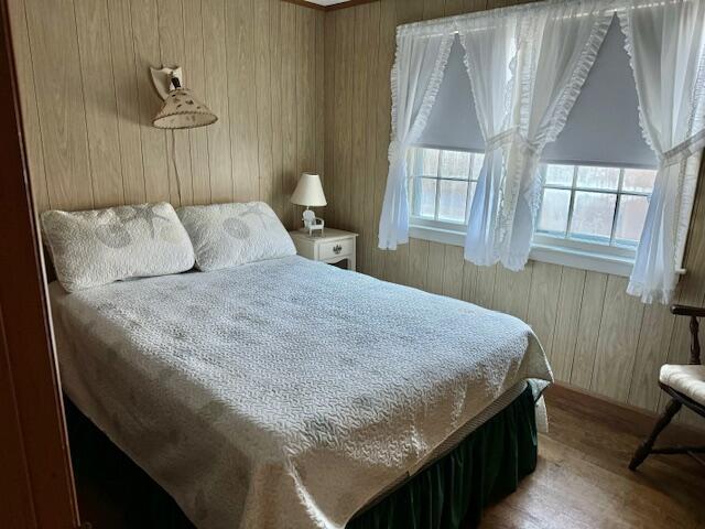 bedroom with hardwood / wood-style flooring and wood walls