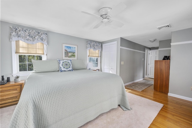 bedroom featuring wood finished floors, baseboards, a ceiling fan, and a closet