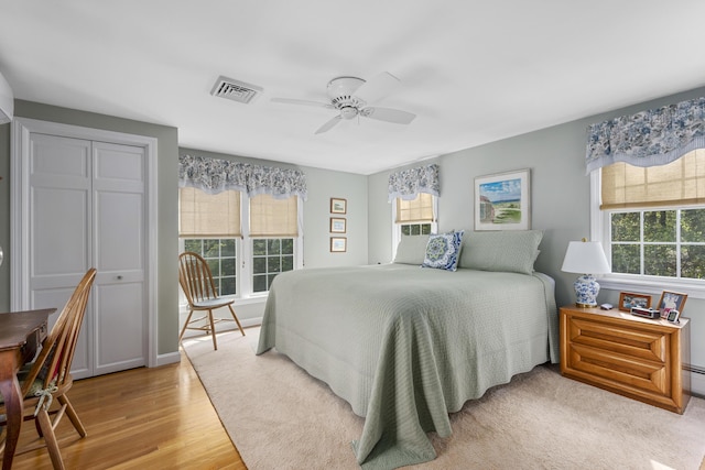 bedroom featuring multiple windows, light wood-type flooring, a closet, and ceiling fan