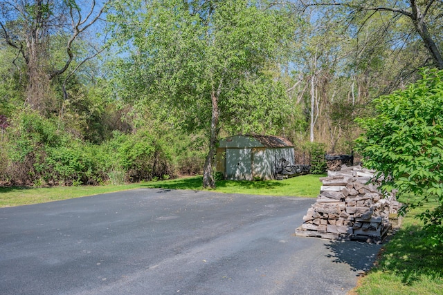 view of yard featuring an outdoor structure, a storage shed, and a view of trees