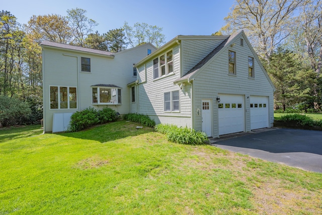 view of property exterior with a garage, driveway, and a lawn