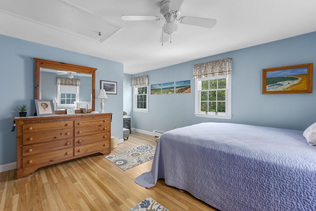 bedroom featuring light wood-type flooring, attic access, baseboards, and a ceiling fan