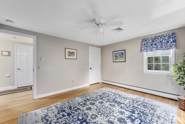 unfurnished room featuring baseboard heating, baseboards, ceiling fan, and wood finished floors