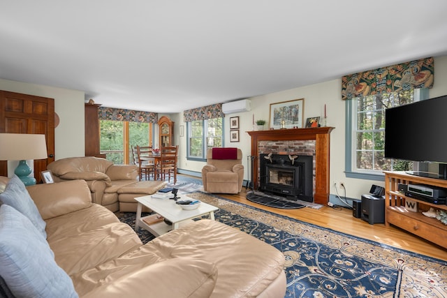 living room featuring a wall mounted AC, wood finished floors, baseboard heating, and a fireplace