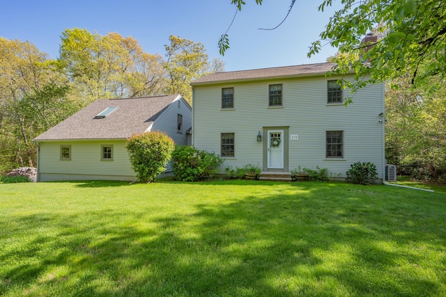 back of house with a chimney, a lawn, and entry steps