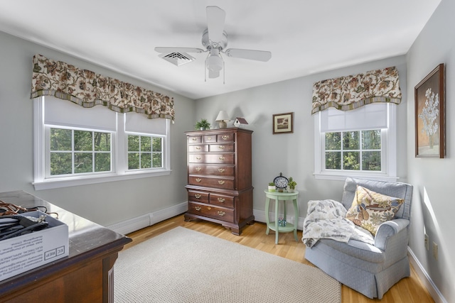 living area featuring light wood-style floors, a ceiling fan, and baseboards