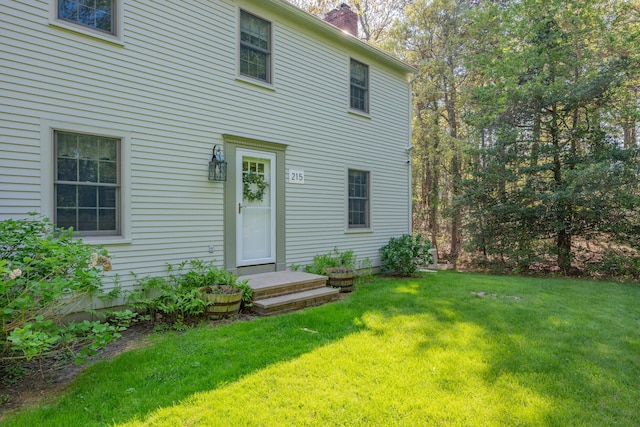 back of property featuring a chimney and a lawn