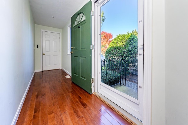 doorway to outside featuring baseboards and dark wood-style floors