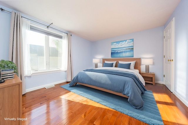 bedroom featuring visible vents, baseboards, and wood finished floors