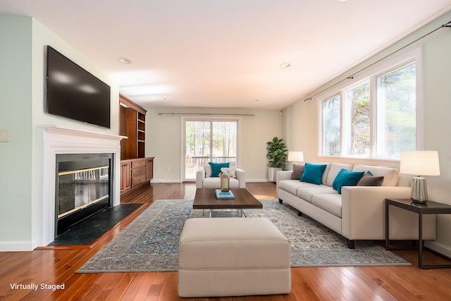 living room with a glass covered fireplace, recessed lighting, baseboards, and hardwood / wood-style flooring