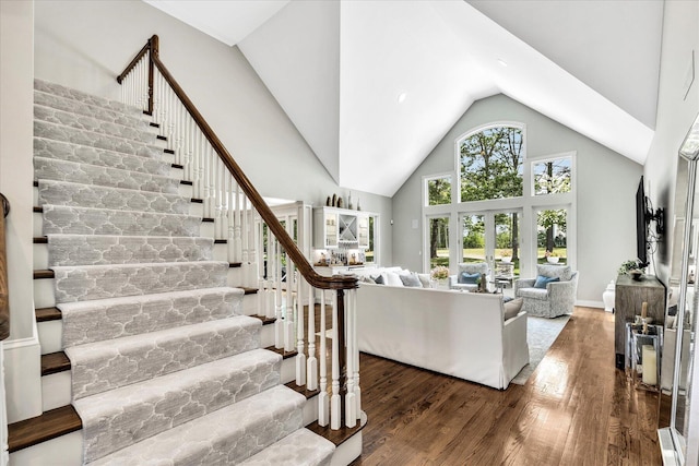 living area featuring high vaulted ceiling, stairs, and wood finished floors