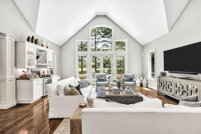 living area with a wealth of natural light, a dry bar, dark wood finished floors, high vaulted ceiling, and beverage cooler
