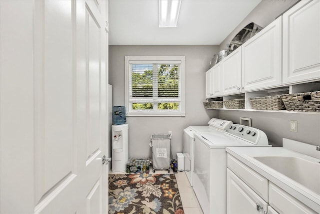 laundry area with light tile patterned flooring, washing machine and dryer, a sink, and cabinet space