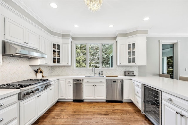 kitchen featuring white cabinetry, under cabinet range hood, stainless steel appliances, beverage cooler, and a sink