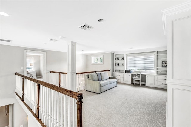 living room featuring crown molding, light colored carpet, built in study area, and visible vents