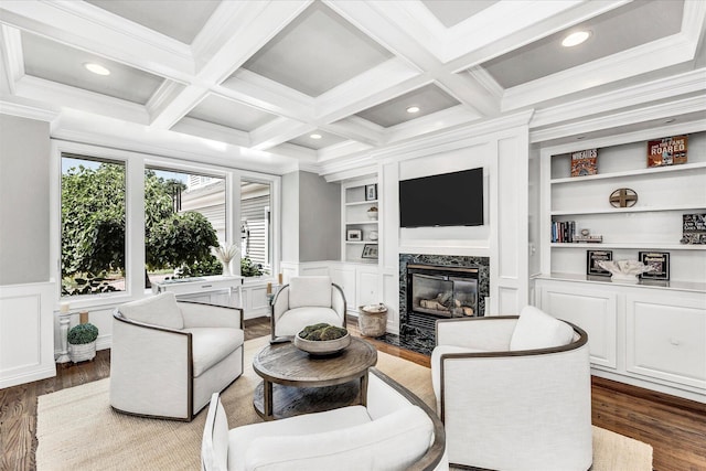 living area with built in features, crown molding, a decorative wall, a high end fireplace, and wood finished floors