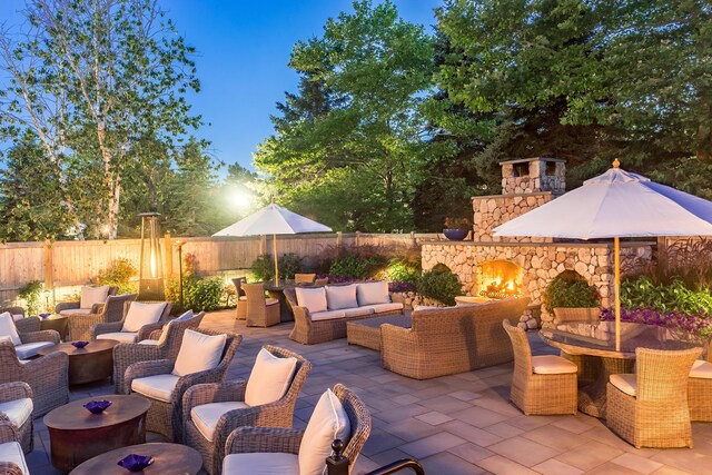 view of patio / terrace with an outdoor living space with a fireplace and fence