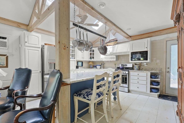 130 Wimbledon Dr, West Yarmouth, MA 02673 - kitchen with appliances with stainless steel finishes, white cabinets, light stone countertops, and a breakfast bar area