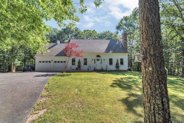 view of front facade featuring an attached garage, a chimney, aphalt driveway, and a front yard