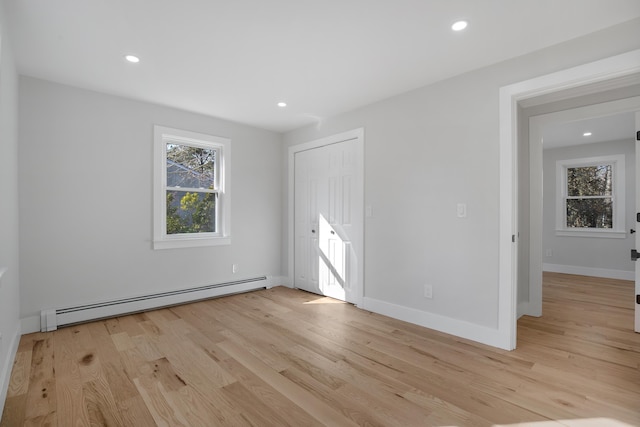 unfurnished bedroom with light wood-type flooring, a baseboard heating unit, and recessed lighting