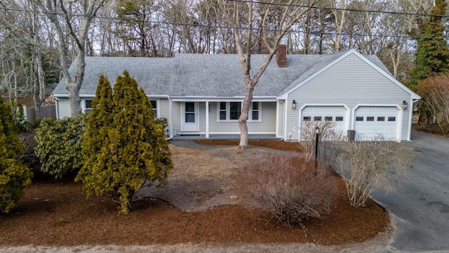 view of front of house with aphalt driveway, a chimney, roof with shingles, and an attached garage