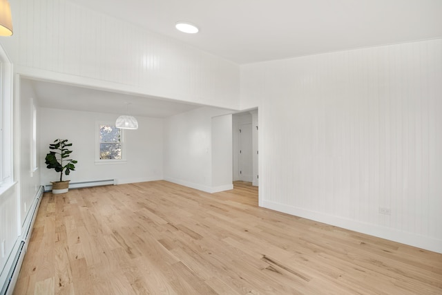 spare room featuring baseboards, baseboard heating, and light wood-style flooring