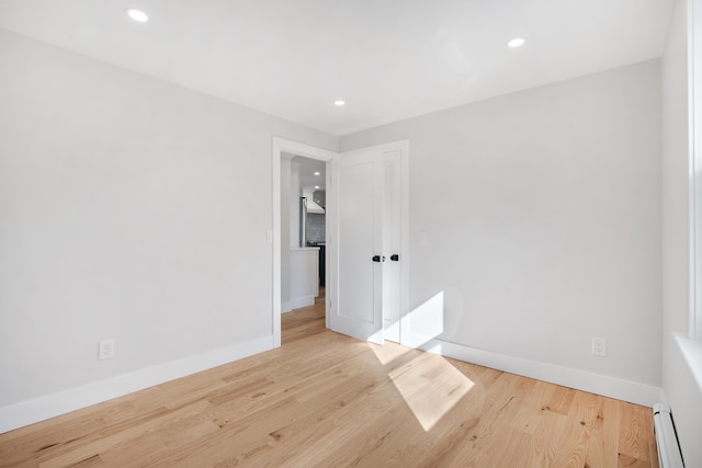 spare room featuring wood finished floors, baseboards, and a baseboard radiator