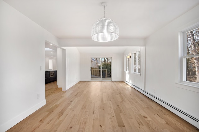 interior space with a baseboard heating unit, an inviting chandelier, a healthy amount of sunlight, and light wood-style floors