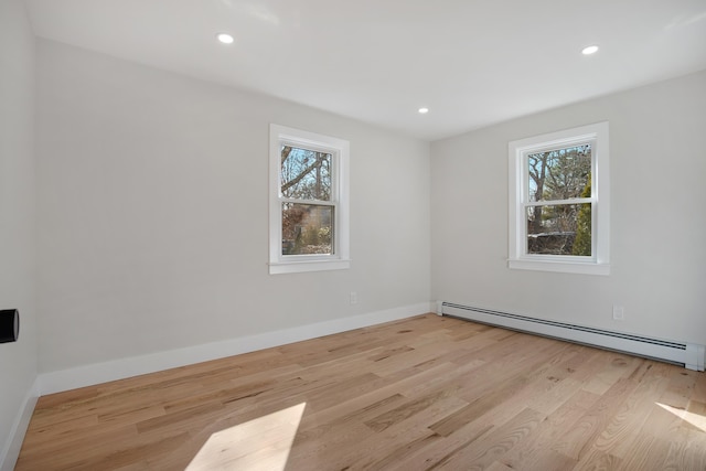 spare room featuring a baseboard radiator, a healthy amount of sunlight, and wood finished floors