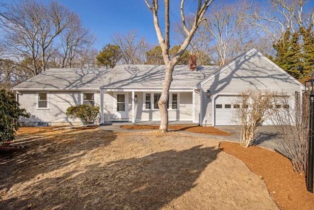 ranch-style home featuring a chimney, a porch, concrete driveway, and a garage