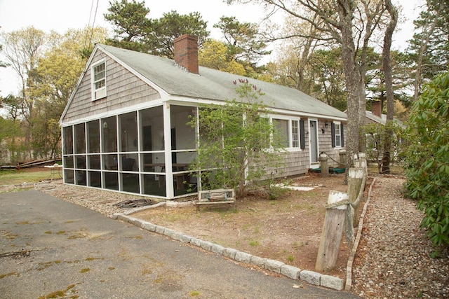 view of side of property with a chimney and a sunroom