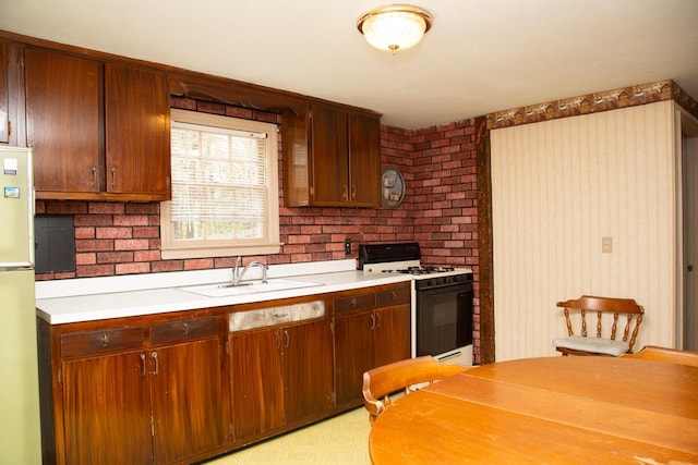kitchen featuring a sink, white appliances, light countertops, and brick wall