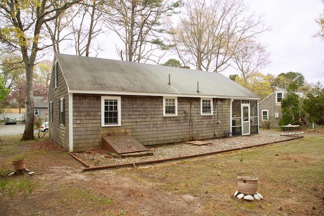 back of property with a sunroom and a shingled roof