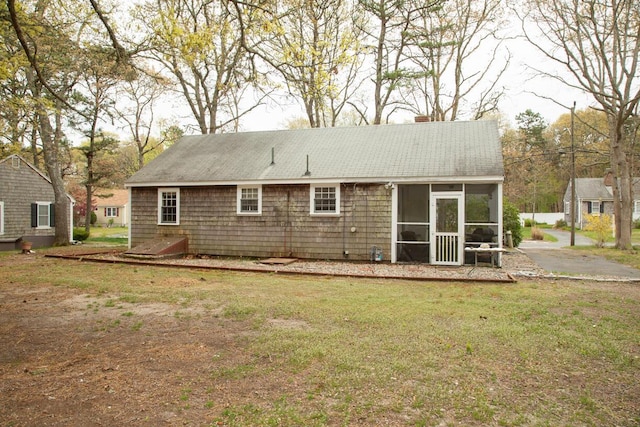 rear view of house with a yard, a sunroom, and a chimney