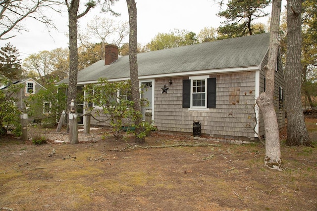 ranch-style house featuring roof with shingles and a chimney