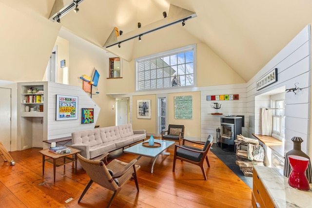 living room featuring plenty of natural light, a wood stove, hardwood / wood-style floors, and high vaulted ceiling