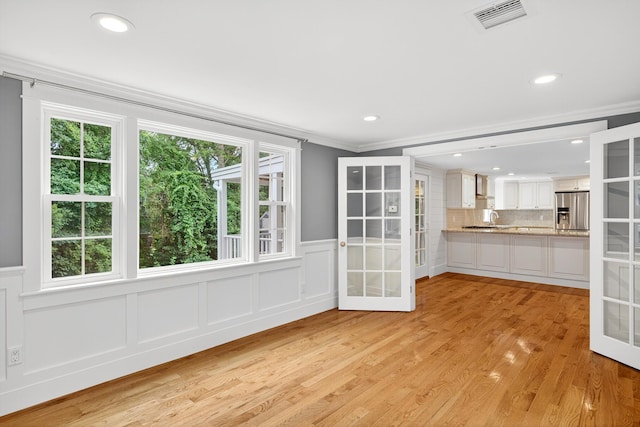 28 Stoney Cliff Rd, Centerville, MA 02632 - unfurnished dining area with ornamental molding, french doors, wainscoting, a decorative wall, and light wood-type flooring