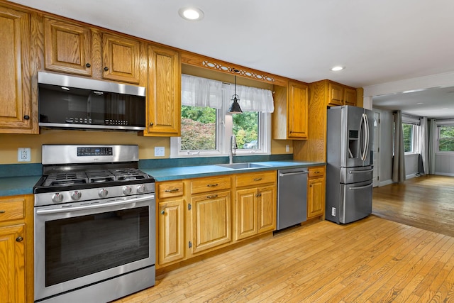 kitchen featuring sink, light hardwood / wood-style floors, appliances with stainless steel finishes, and pendant lighting