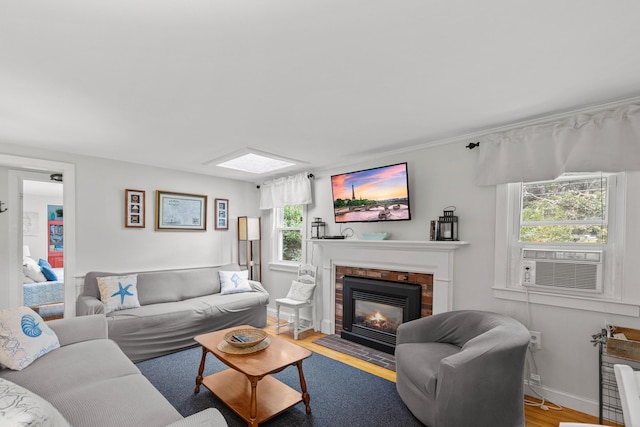 living room featuring a brick fireplace, plenty of natural light, cooling unit, and light hardwood / wood-style flooring