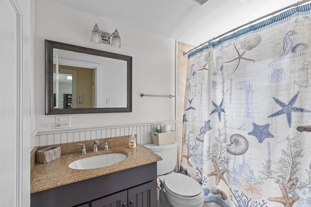 bathroom featuring toilet, vanity, and a shower with curtain