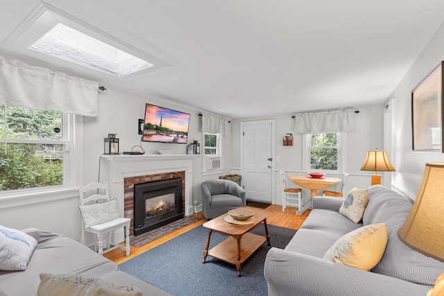 living room featuring a skylight, a fireplace, and wood-type flooring