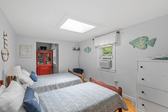 bedroom with a skylight and light hardwood / wood-style flooring