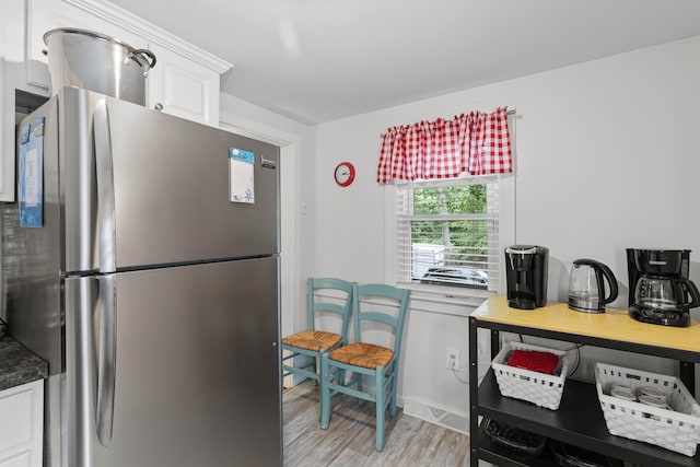 kitchen with white cabinets, light hardwood / wood-style flooring, and stainless steel refrigerator