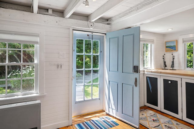 doorway to outside with wood ceiling, beam ceiling, wooden walls, and light wood-type flooring