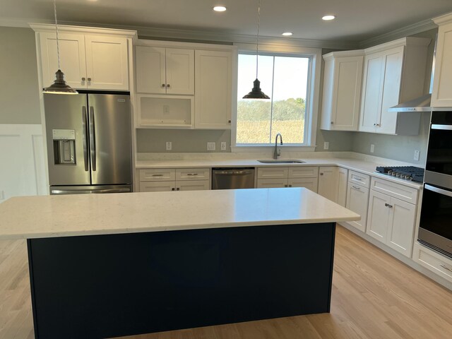 kitchen with hanging light fixtures, appliances with stainless steel finishes, sink, white cabinets, and a center island